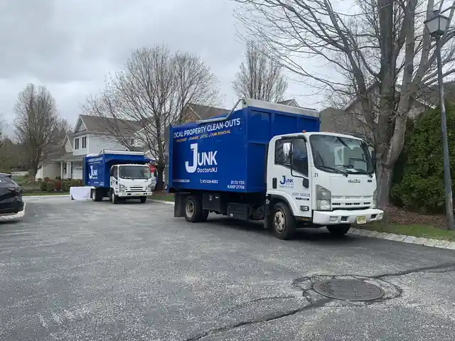 Two JunkDoctors box trucks parked side by side in a residential lot