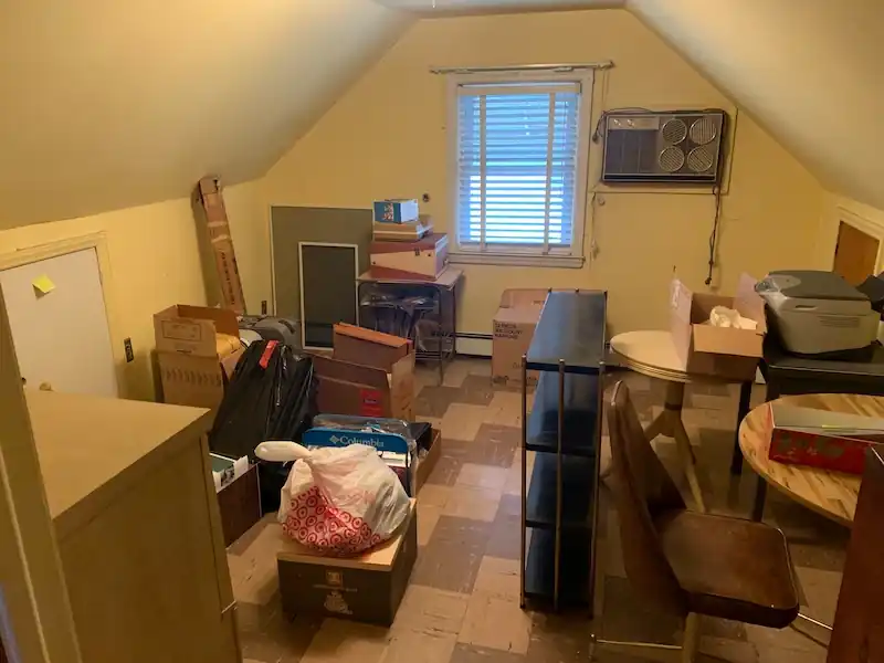 Glen Ridge attic room filled with boxes, a bookshelf and stacked furniture