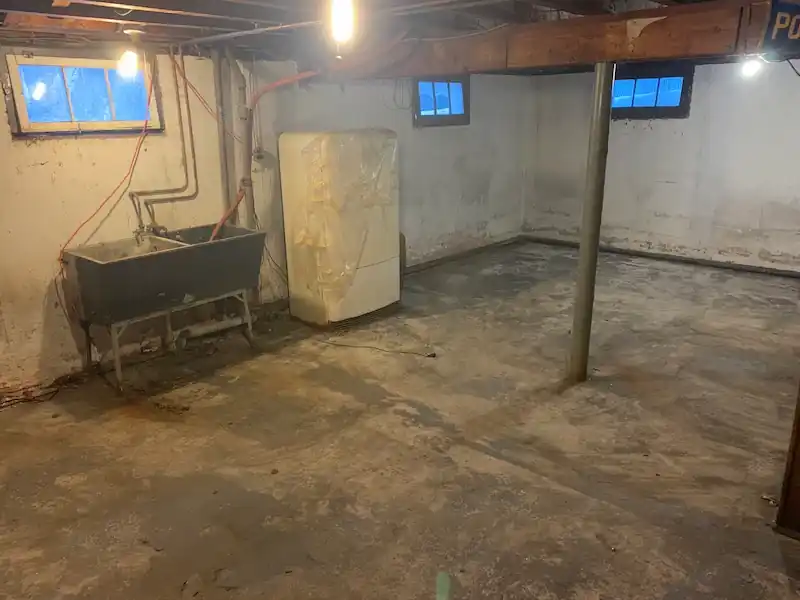 Basement laundry corner with a white appliance beside a utility sink