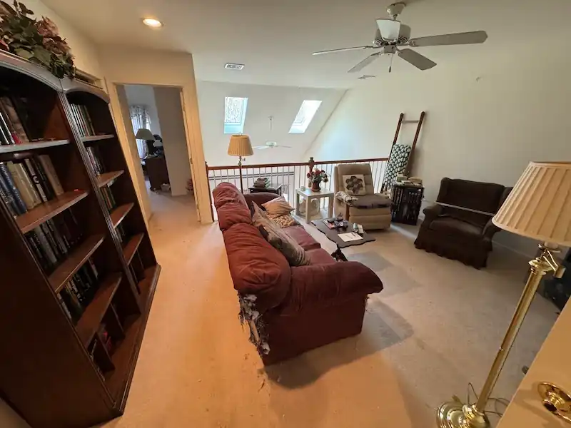 Estate living room with a red sofa, armchair and full bookcase before clearing