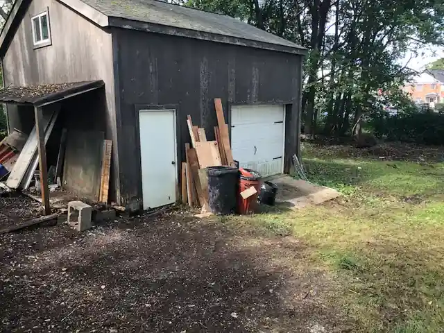 Phillipsburg barn shed with lumber stacked against it and the yard cleared