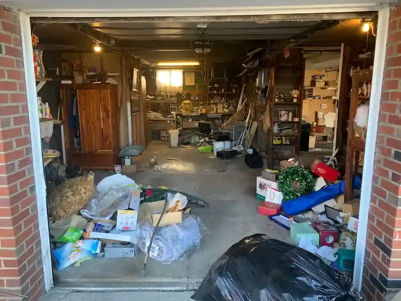 Two-car garage in Hasbrouck Heights packed with bags, boxes and furniture before the cleanout