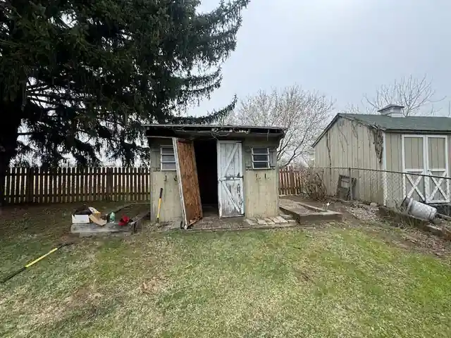 Old wooden shed in a fenced backyard before demolition