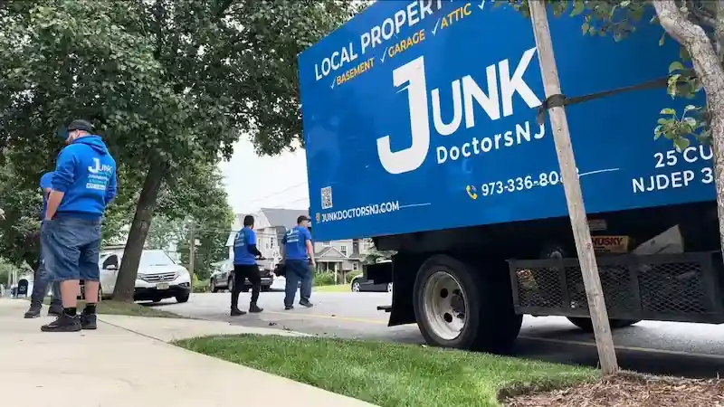 JunkDoctors crew standing beside their blue truck in Ridgewood