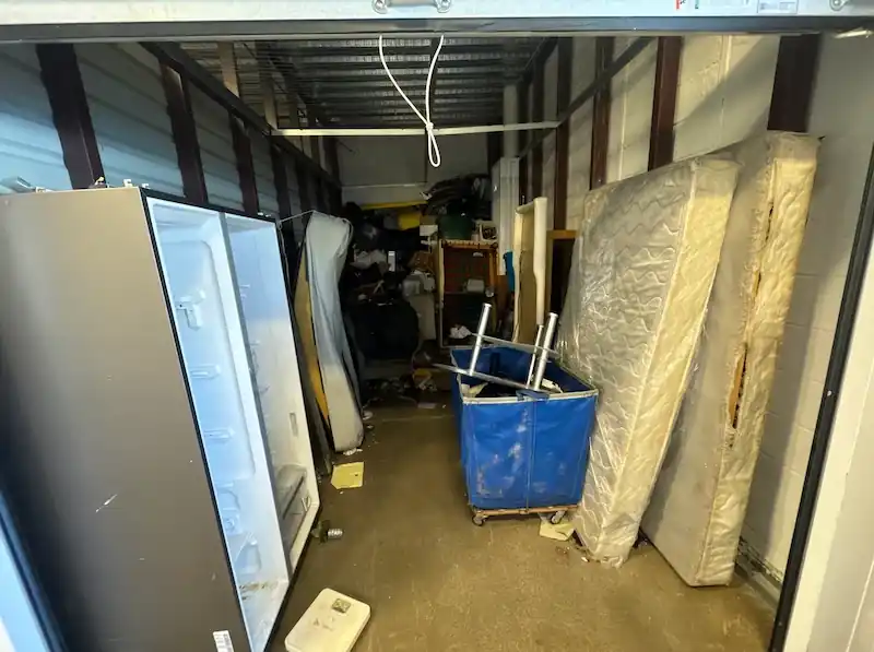 Woodbridge storage unit holding a refrigerator, mattresses and a laundry cart
